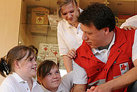 Kinder mit einem Mann in einer DRK Uniform 
