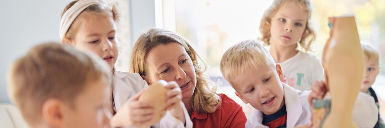 Erzieherin zeigt einer Gruppe Kinder die menschlichen Organe am Beispiel eines Torsos