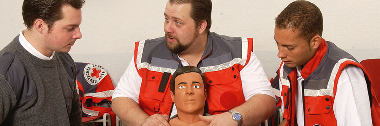 Ein Mann und zwei Männer in DRK Uniform 