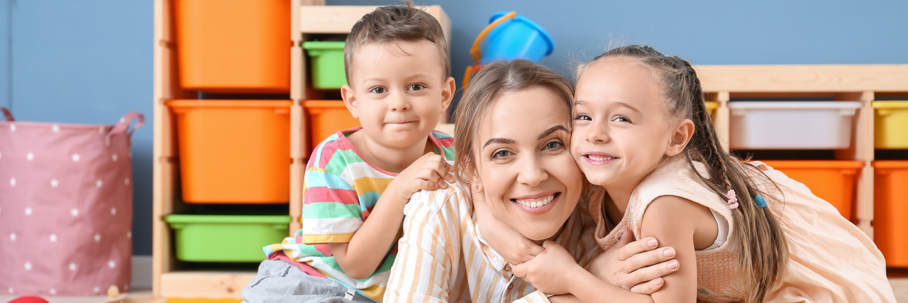 Frau mit zwei Kindern, sie lachen in die Kamera